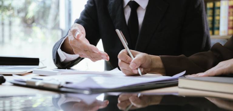 male lawyer working with contract documents and wooden hammer on table in courtroom